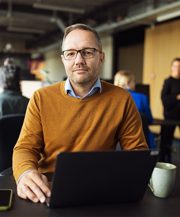 Mand sidder med computer i åbent kontorlandskab